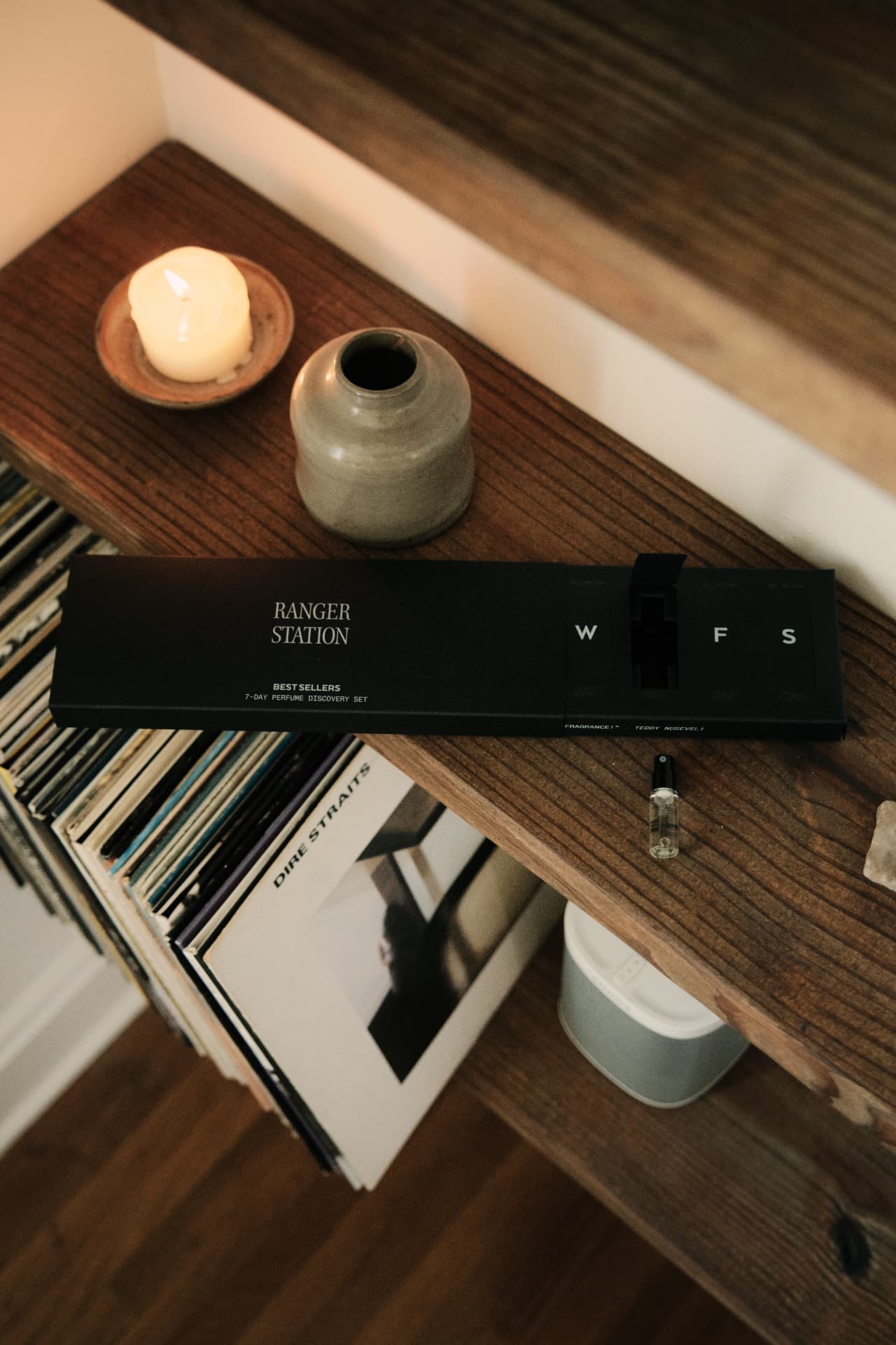 The Best Sellers seven-day set resting on a walnut shelf beside a candle and a stack of records