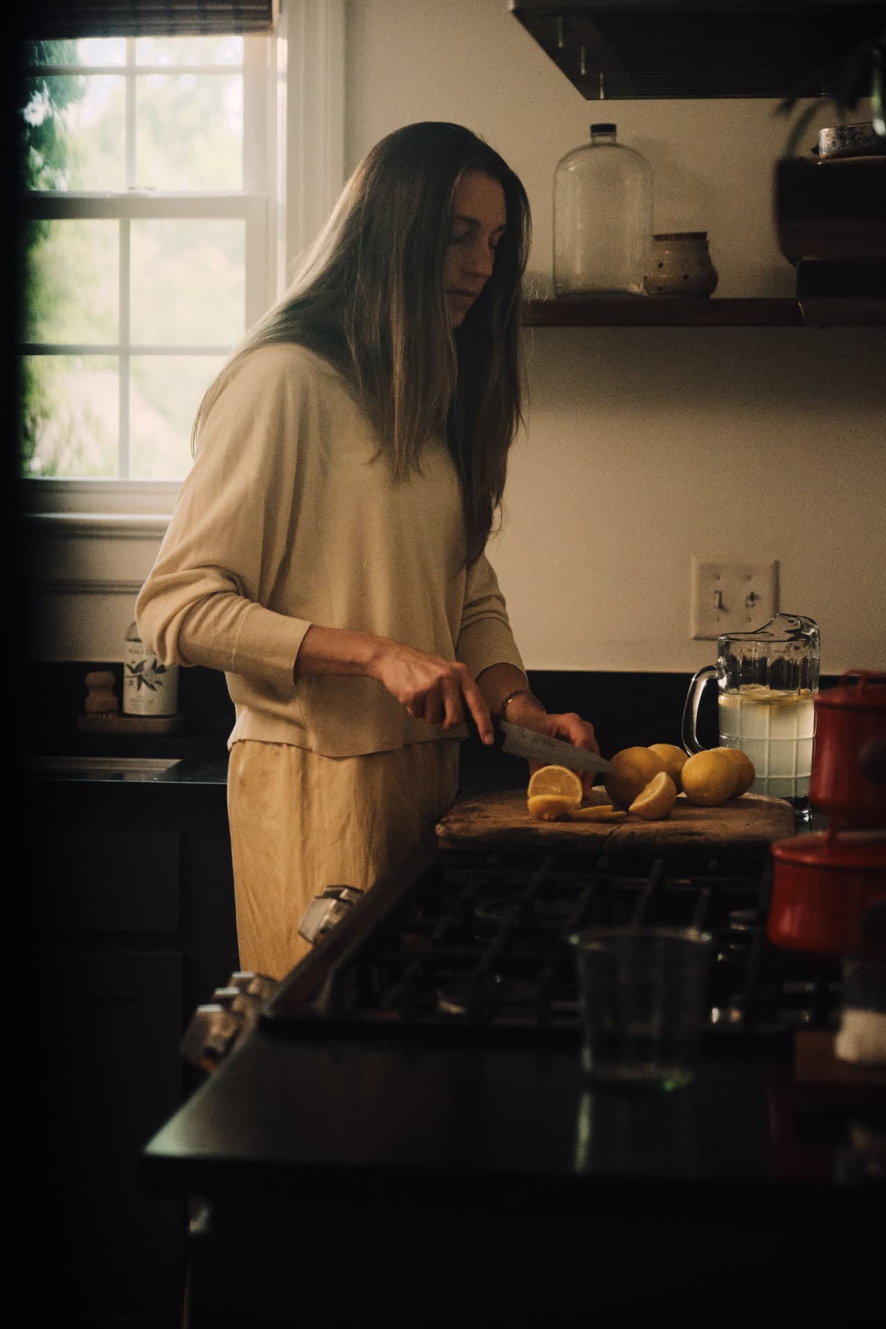 Morning light in a kitchen as lemons are sliced on a worn cutting board